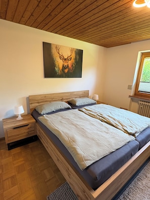 Ein Schlafzimmer mit Holzboden, einem Bett mit Kopfteil, einem Nachttisch, einer Lampe und einem Bild an der Wand.