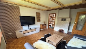 Un salon moderne doté d’un téléviseur à écran plat, de parquet, d’un canapé, d’une table basse et d’une cheminée.