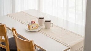 A table with a cake, two coffee cups, and a chair. - Pohang Baritdol Pension (Pohang)