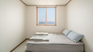 A bedroom with a bed, a window with a view of the sea, and a sloped ceiling. - Pohang Baritdol Pension (Pohang)