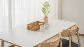 A white table with a wicker basket, two white mugs, and a green plant in a vase. - Pohang Baritdol Pension (Pohang)