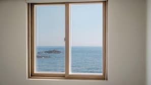 A window with a view of the sea and a rocky outcrop. - Pohang Baritdol Pension (Pohang)