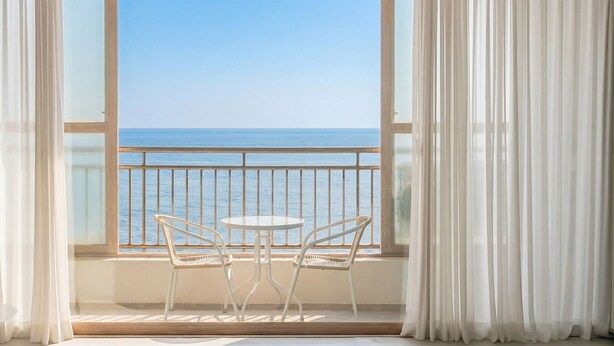 A balcony with two chairs and a table, overlooking the sea. - Pohang Baritdol Pension (Pohang)
