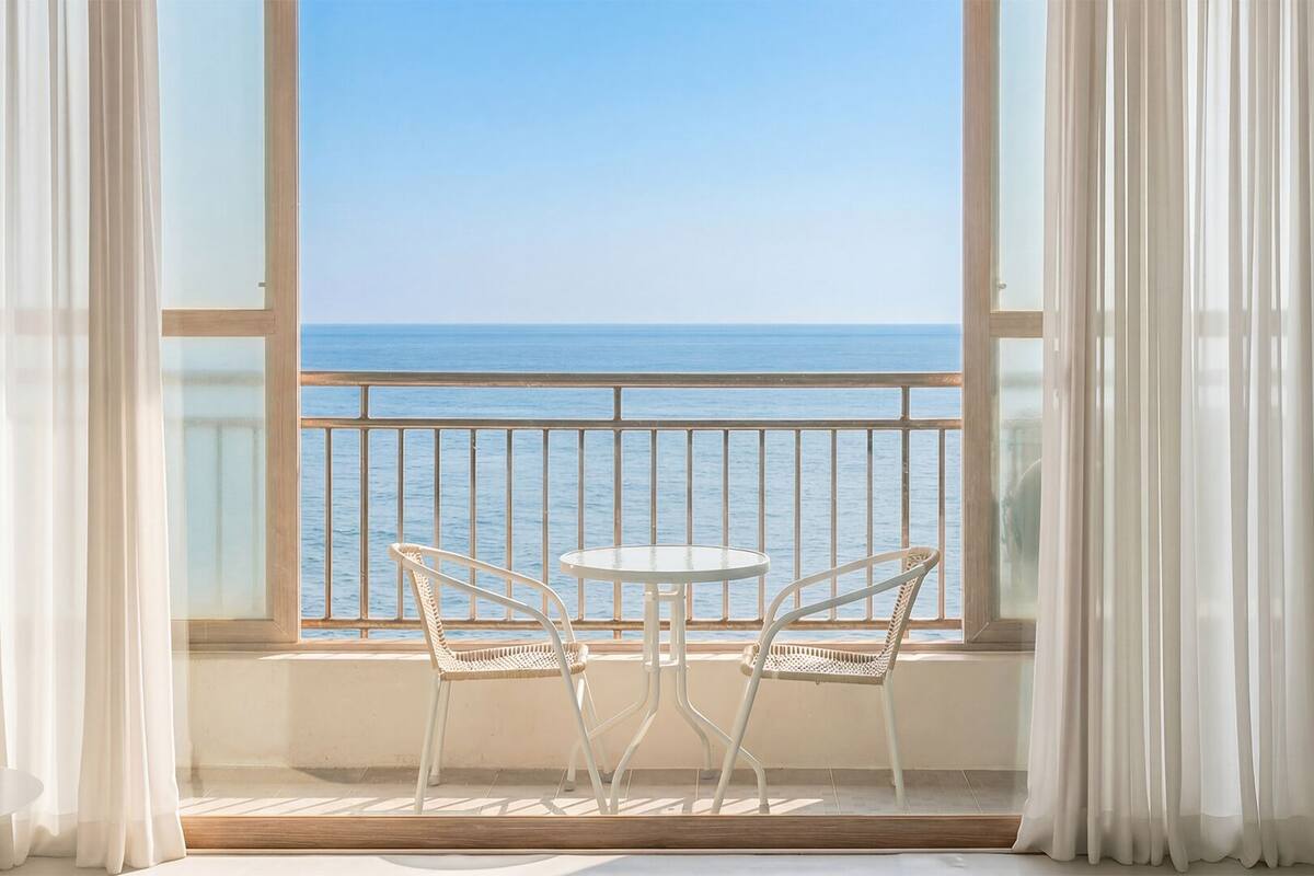 A balcony with two chairs and a table, overlooking the sea.