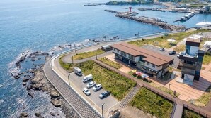A coastal building with a parking area, a road, and a view of the sea. - Pohang Baritdol Pension (Pohang)