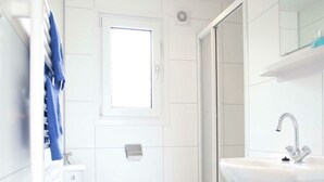 Ein Badezimmer mit Toilette, Waschbecken, Spiegel und Dusche.