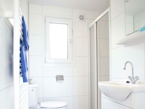 Ein Badezimmer mit Toilette, Waschbecken, Spiegel und Dusche.