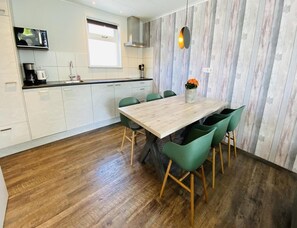 Eine moderne Küche mit weißen Schränken, einem Holzespeisetisch, grünen Stühlen und einer Mikrowelle.