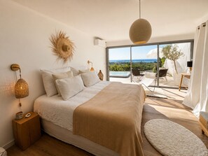 A bedroom with a large bed, a balcony with a hot tub, and a view of the landscape. - Panoramic sea view house with private jacuzzi between Antibes and Cannes (Vallauris)