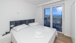 A modern hotel room with a large bed, a bedside phone, and a balcony with a city view. - Altiora Prestige Residence 202 (Gradac)