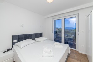 Ein modernes Hotelzimmer mit einem großen Bett, einem Nachttischtelefon und einem Balkon mit Blick auf die Stadt.