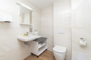 Ein modernes Badezimmer mit Waschbecken, Spiegel und Toilette in Weiß.