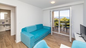 A modern room with a blue sofa, a small table, and a TV. - Altiora Prestige Residence 202 (Gradac)