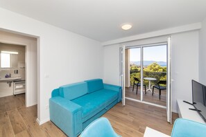 Ein modernes Zimmer mit einem blauen Sofa, einem kleinen Tisch und einem Fernseher.