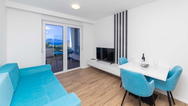 A modern living room with a sofa, TV, and dining area with chairs. - Altiora Prestige Residence 202 (Gradac)