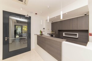 Eine moderne Küche mit dunkler Holz Arbeitsplatte, einer Glastür und Blick ins Freie.