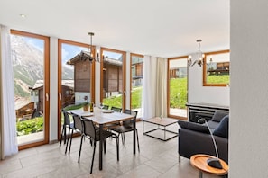 Ein modernes Interieur mit Essbereich, einer Couch und Blick auf einen Berg.