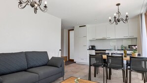 Una sala moderna con sofá, mesa de comedor, sillas y una cocina al fondo.