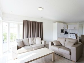 A modern living room with two sofas, a coffee table, and a kitchen in the background. - Holiday Home in Breskens With Terrace (Breskens)