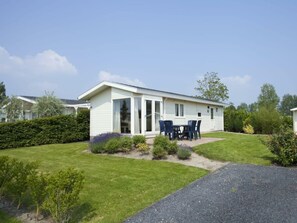 A single-story mobile home with a patio area, a small garden, and a gravel driveway. - Holiday Home in Breskens With Terrace (Breskens)