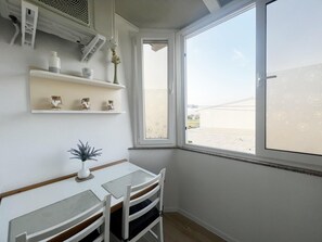 A room with a table and chairs, a window with a view, and shelves with decorative items. - Apartment Lavaran 5 (Vir)