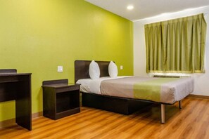 Une chambre d’hôtel avec un lit, un bureau, une table de chevet et une fenêtre avec des rideaux.