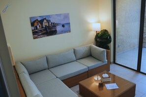 A living room with a sofa, a coffee table, a painting, a lamp, and a plant.