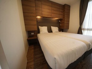 Ein Schlafzimmer mit einem großen Bett, einem Holzkopfende, Nachttischen und einem Beistelltisch.