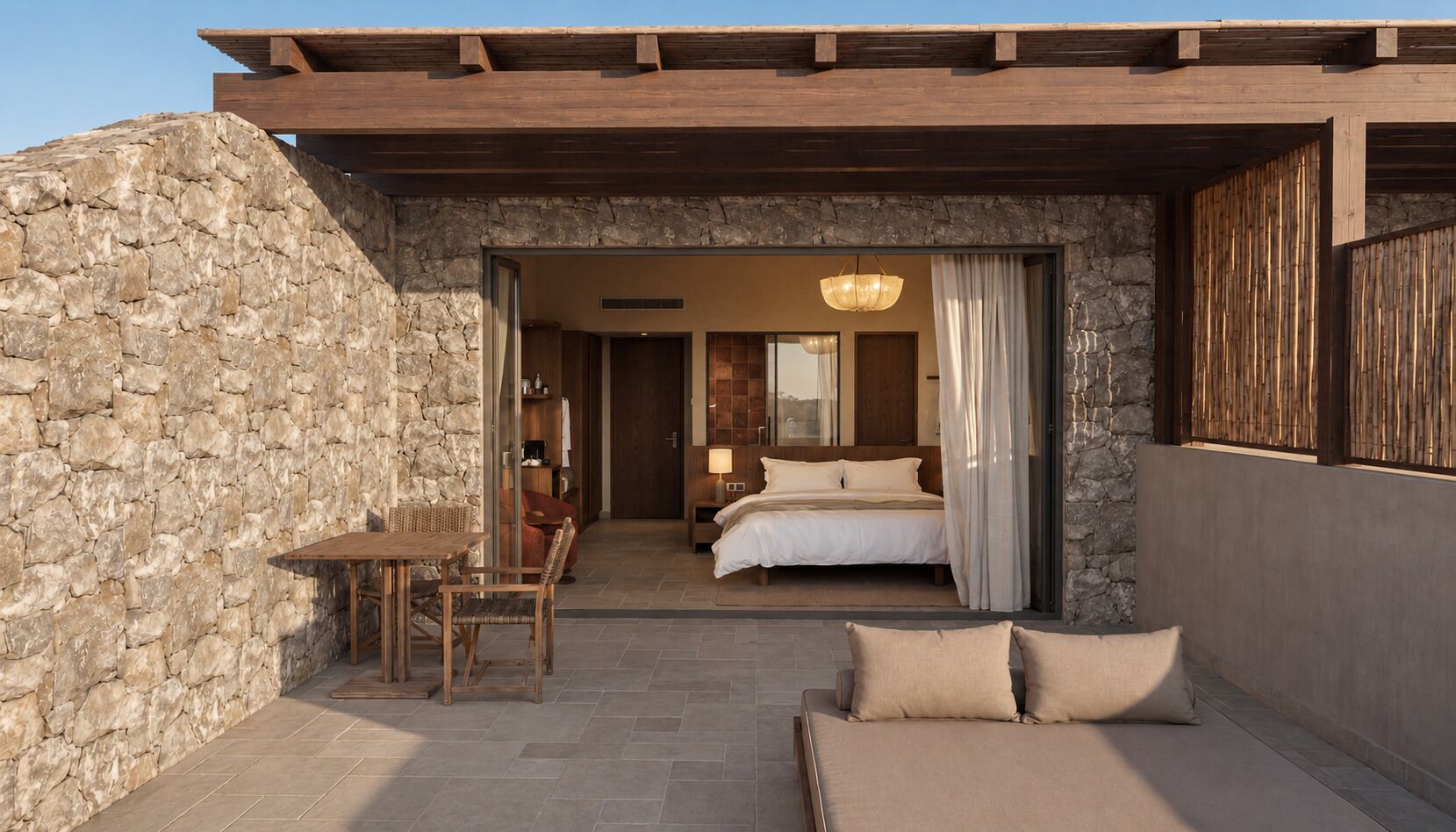 A stone exterior wall, a wooden table with chairs, a bed with white bedding, and a sofa with cushions.