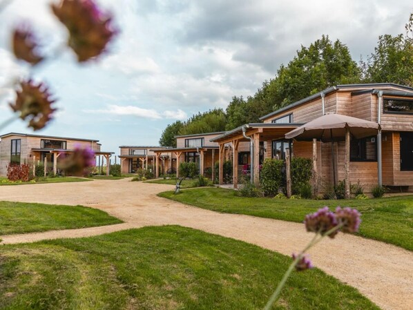 A row of modern, wooden cabins with covered outdoor seating areas, arranged in a linear fashion along a gravel path. - Holiday Home in Warmond With Terrace (Warmond)