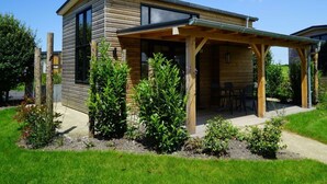 A modern wooden house with a covered patio, surrounded by well-maintained greenery. - Holiday Home in Warmond With Terrace (Warmond)