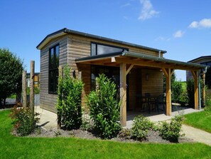 A modern wooden house with a covered patio, surrounded by well-maintained greenery. - Holiday Home in Warmond With Terrace (Warmond)