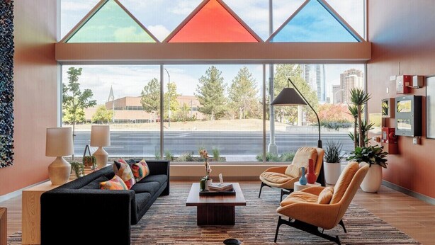 A modern living room with a large window, a sofa, a coffee table, and two armchairs. - Charming apartment in pleasant Denver with cool AC and fitness room (Denver)