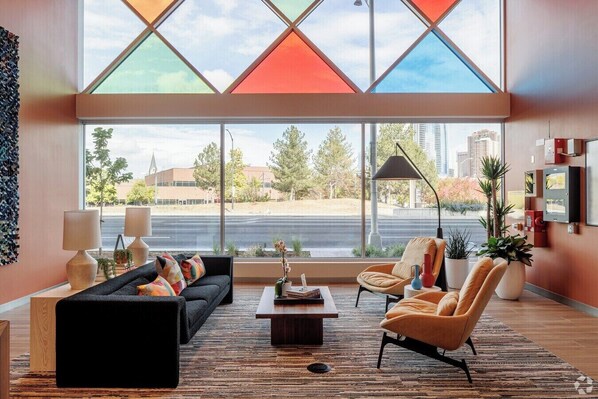 A modern living room with a large window, a sofa, a coffee table, and two armchairs.