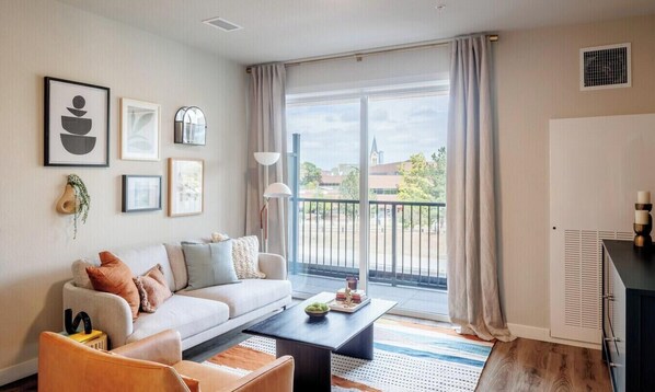 A modern living room with a sofa, coffee table, and artwork on the wall. - Charming apartment in pleasant Denver with cool AC and fitness room (Denver)