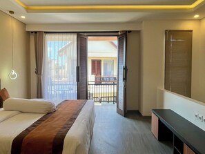 Habitación de hotel con cama, escritorio, vista al balcón y ventana con persianas.