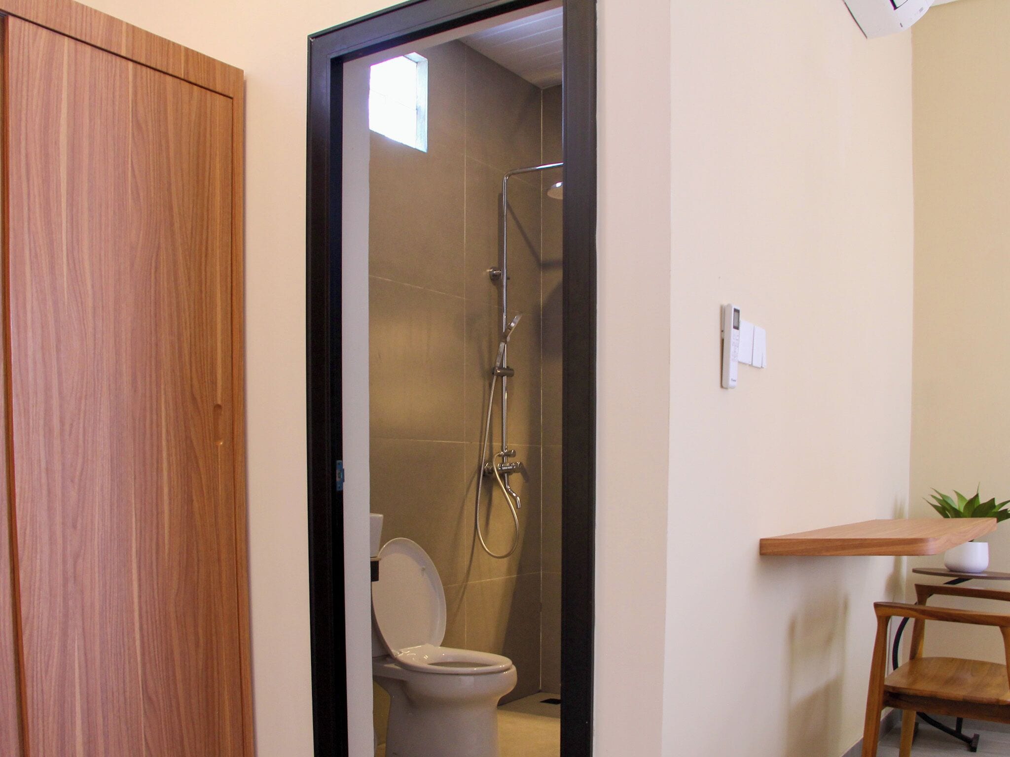 Une salle de bain avec des toilettes, une douche et un meuble en bois.