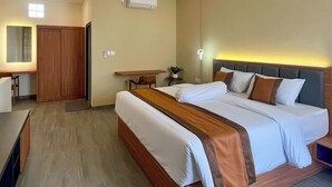 Hotellihuone, jossa on sänky, työpöytä, tuoli, vaatekaappi ja ilmastointilaite.