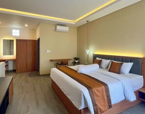 Habitación de hotel con cama, escritorio, silla, armario y equipo de aire acondicionado.