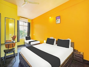 A hotel room with a large bed, a smaller bed, a chair, a desk, a mirror, and a window with curtains. - Deluxe Collection O Coorg Arvind Premium (Somvarpet)