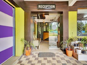A reception area with a sign, a bench, and potted plants. - Deluxe Collection O Coorg Arvind Premium (Somvarpet)