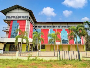A multi-story building with a flat roof, large windows, and a green and red facade. - Deluxe Collection O Coorg Arvind Premium (Somvarpet)
