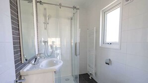 A bathroom with a glass shower enclosure, a sink, a toilet, and a window. - Holiday Home in Maarn With Terrace (Maarn)