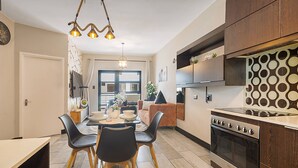 Een moderne keuken met een eethoek, houten kastjes en een inbouwoven.