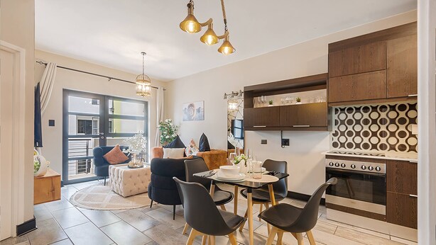 Een moderne keuken met een eethoek, met een ronde tafel, stoelen en een inbouwoven.