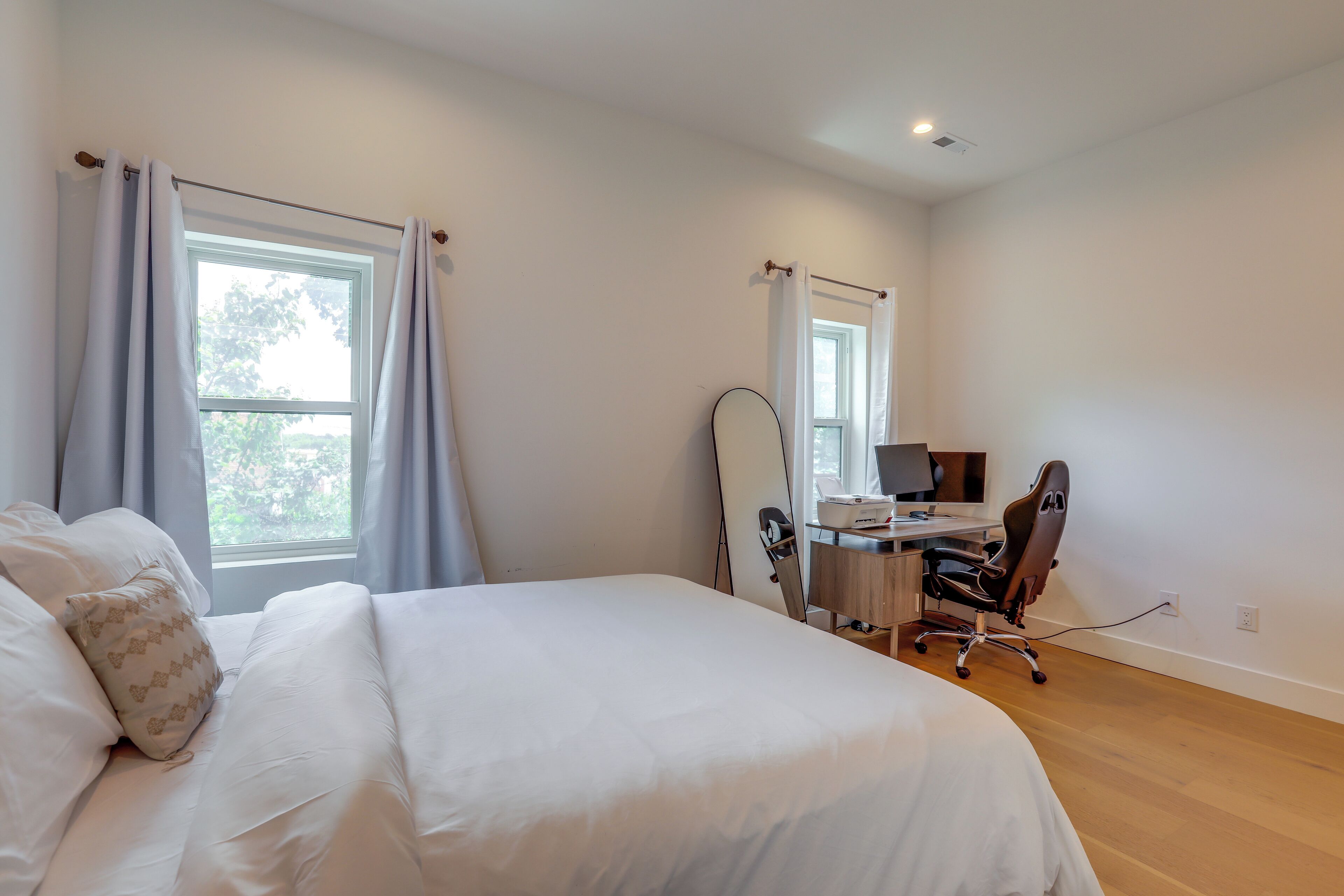 Un dormitorio con cama, escritorio, silla y ventana.