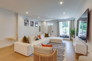 Uma sala de estar moderna com um sofá seccional, uma poltrona de vime e uma janela grande com cortinas.
