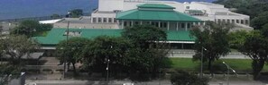 A large building with a green roof, surrounded by trees and a fence. - Grand Riviera neas Slec (Manila)