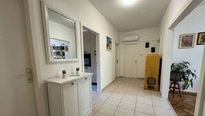 Ein Flur mit einem weißen Schminktisch, einem Spiegel, einem Fliesenboden und einem gelben Schrank.