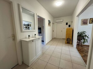 Ein Flur mit einem weißen Schminktisch, einem Spiegel, einem Fliesenboden und einem gelben Schrank.